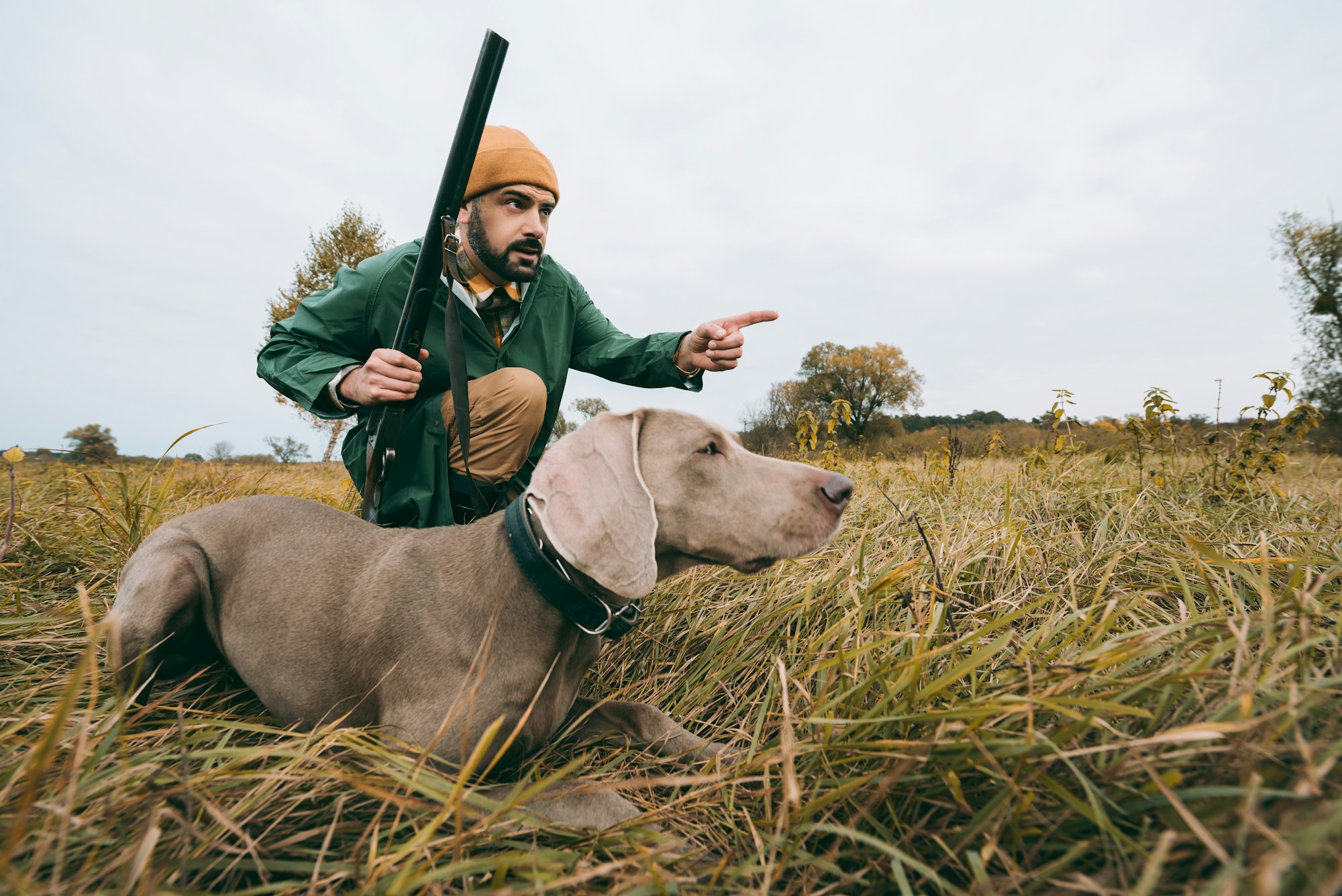 handsome man squatting with a dog and hunting down an animal